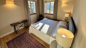 A bedroom with a bed, bedside lamps, a desk, and a window. - Villa 16 (Bagno A Ripoli)