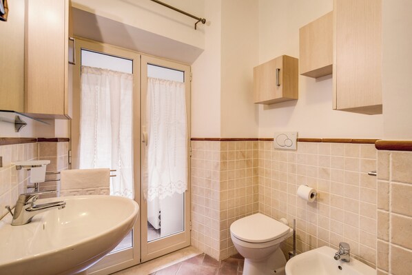 A bathroom with a large sink, toilet, and bidet. There is a towel rack and a mirror above the sink. - 2 apartments Campo de Fiori, with terrace (Roma)
