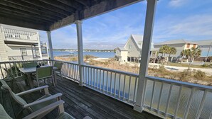 Eine Holzterrasse mit Sitzgelegenheiten im Freien, mit Blick auf einen Strand und das Wasser.