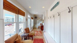Ein Flur mit Blick auf den Strand, eine Treppe und ein Schild mit der Aufschrift 'BEACH HOUSE'.