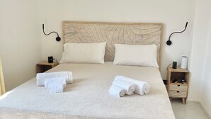 A neatly made bed with white linens and towels, a wooden headboard, and a bedside table with a lamp. - Evelyn's Pool Garden (Forio)