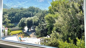 A view from a window overlooking a mountainous landscape with dense greenery and a clear blue sky. - Evelyn's Pool Garden (Forio)