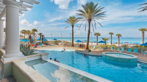 A pool area with palm trees, lounge chairs, and umbrellas. - 🏖️XL Balcony with Awesome View-Beachfront Pool-3BR Boardwalk 2101🏖️ (Panama City Beach)