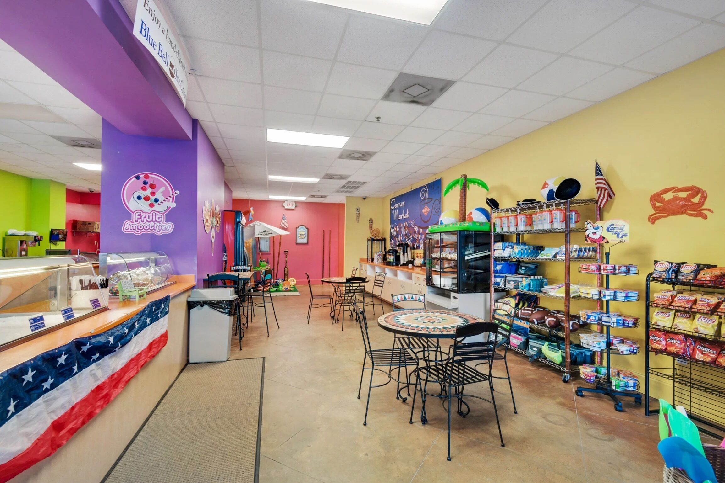 A brightly colored food court with a variety of seating options and food displays.