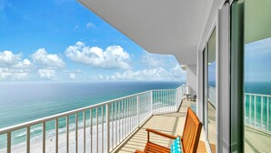 A balcony with a wooden bench and a table, overlooking a beach and the ocean. - 🏖️XL Balcony with Awesome View-Beachfront Pool-3BR Boardwalk 2101🏖️ (Panama City Beach)
