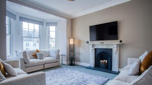 A living room with a fireplace, a flat-screen TV, and a sofa set. - The Lanterns - 9 Bedroom - Sleeps 17 - Saundersfoot Village Centre (Saundersfoot)