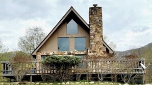 A house with a stone chimney, a large window, and a wooden deck. - TF26-Quaint Cottage! Pets Ok! Fire Pit! (Davis)