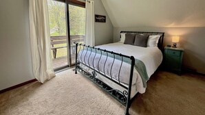 A bedroom with a bed, a nightstand, a lamp, a window with curtains, and a view of the outdoors. - TF26-Quaint Cottage! Pets Ok! Fire Pit! (Davis)