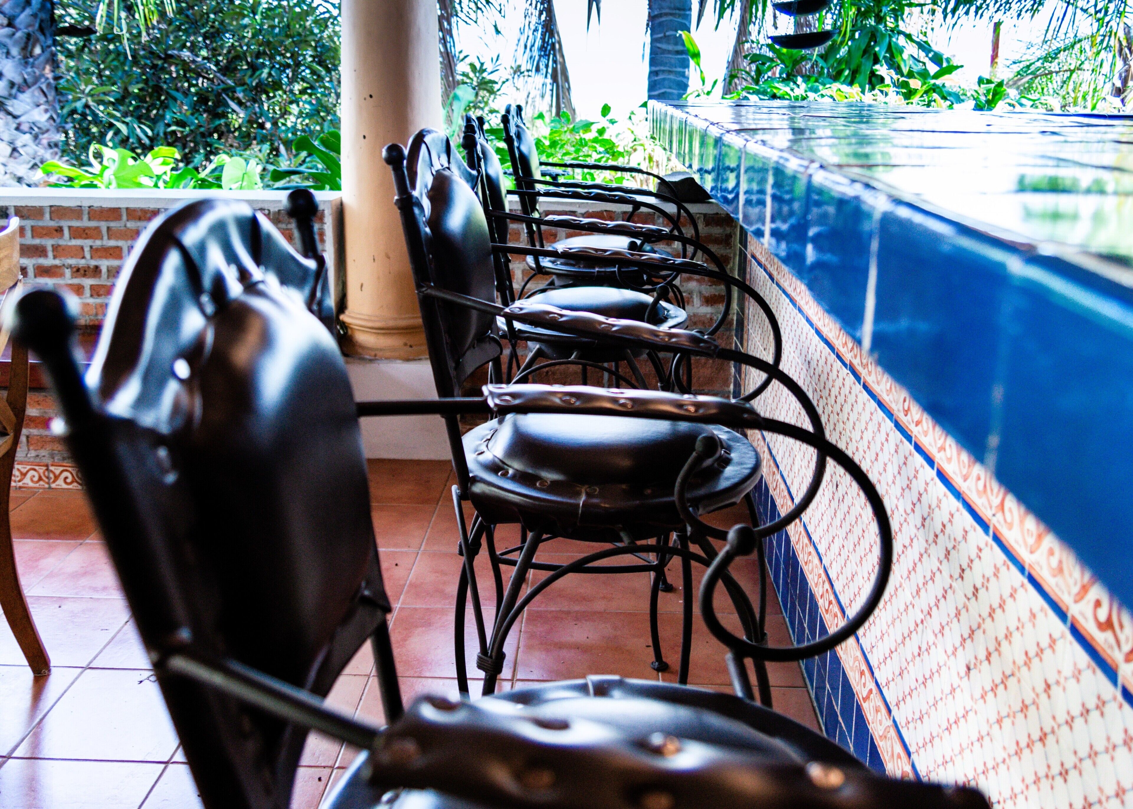 A row of black metal chairs with a tiled wall and a tiled floor.