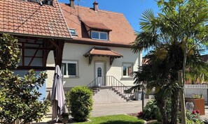Ein zweistöckiges Haus mit Ziegeldach, einer Haustür und einer Treppe, die zum Eingang führt.