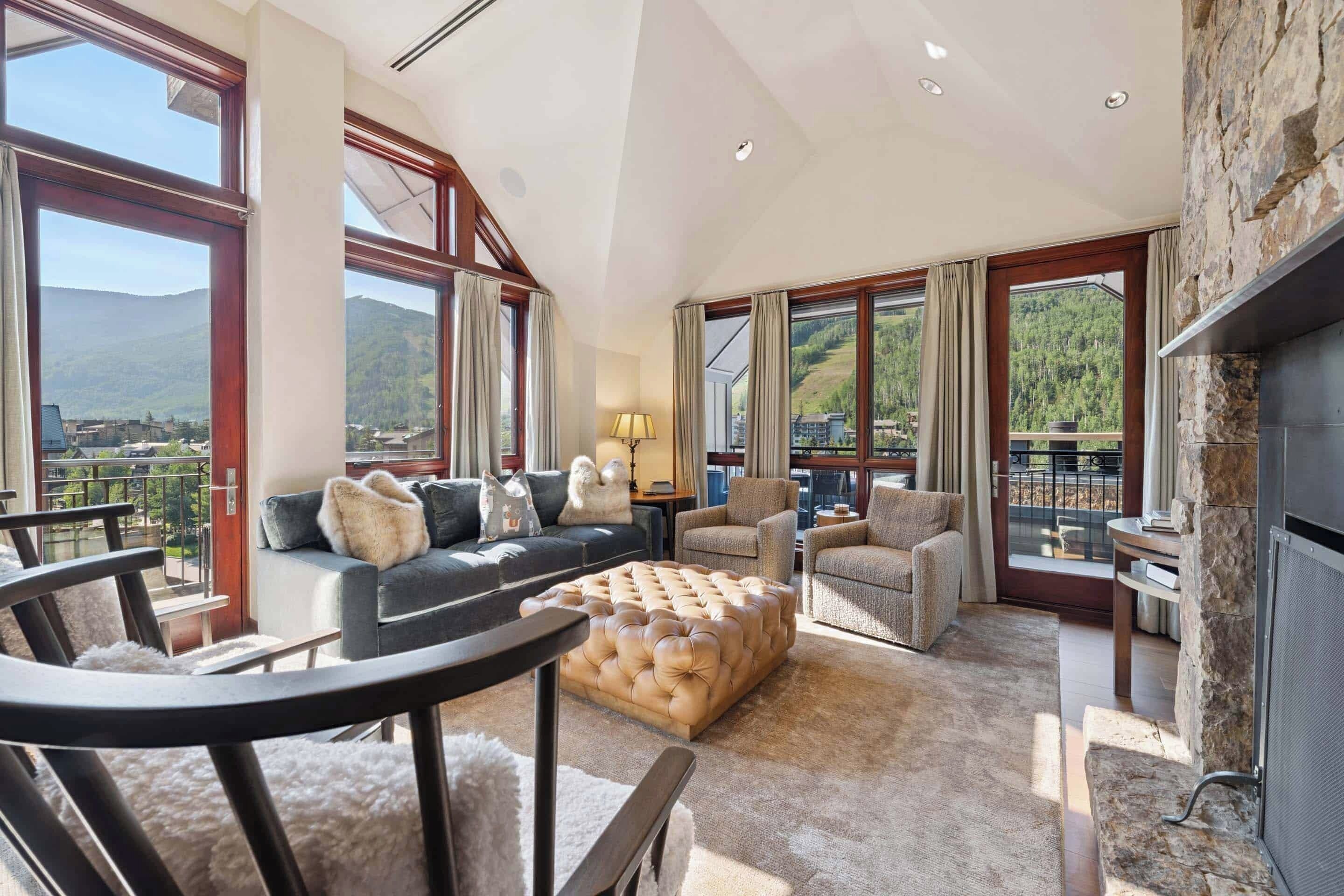 A spacious living room with a large window, a fireplace, and a view of mountains.