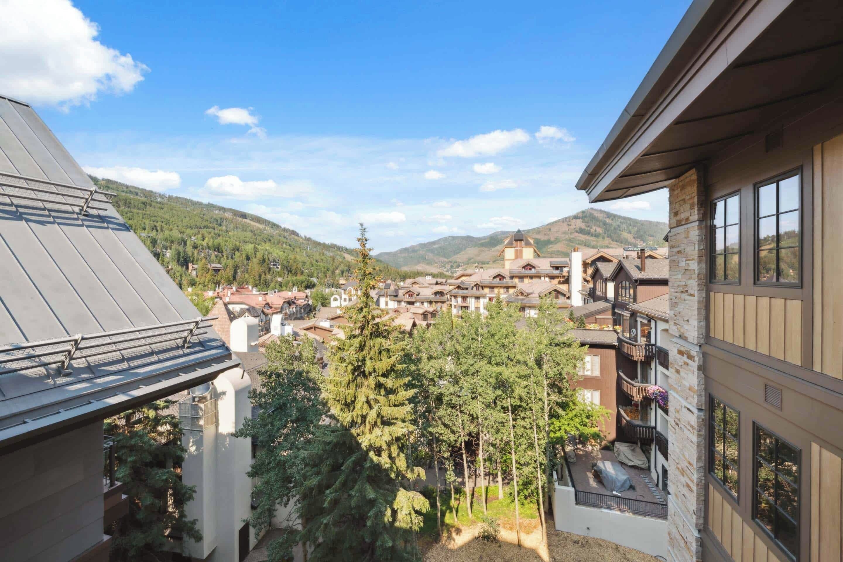 A view of a mountain town with buildings, trees, and a clear sky.