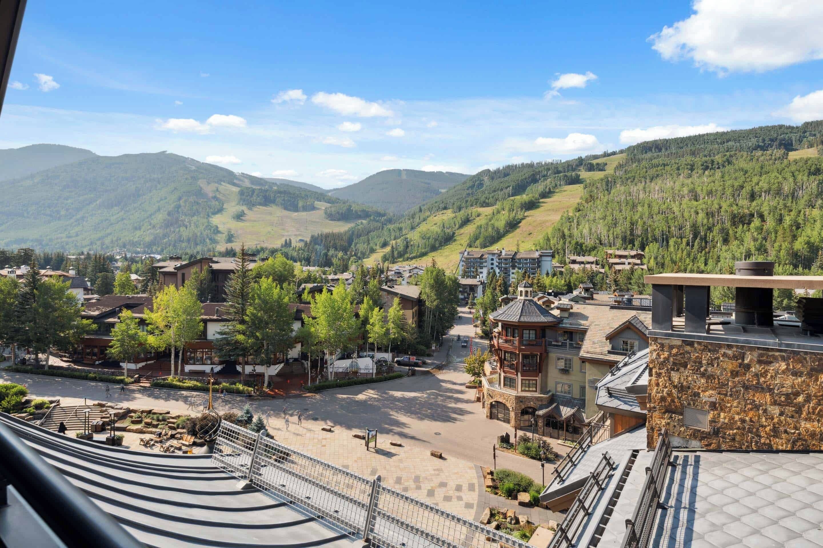 Une ville de montagne avec des bâtiments, une place centrale et une vue sur les collines environnantes.