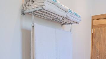 A bathroom with a towel rack holding folded towels and a towel with "Villa Maria" written on it.