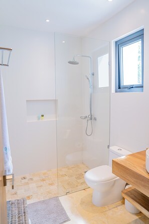 A modern bathroom with a glass shower enclosure, a white toilet, and a wooden vanity. - Premium 2-bedroom Townhome with Private Pool & Golf View in awesome Puerto Plata (Puerto Plata)