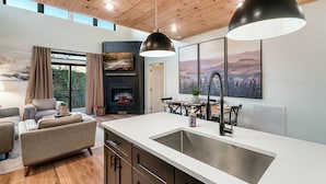 A modern kitchen with a large island, wooden ceiling, and a fireplace. - Location! New Indoor POOL Cabin! Sunset Mnt View! Hot tub, Games, Bunk Room! (Sevierville)