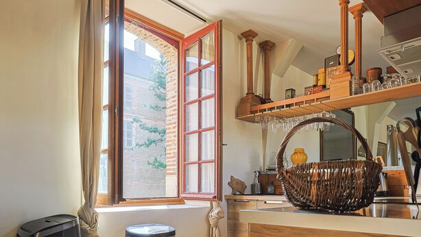 Una cocina con un amplio ventanal, estantes de madera y una cesta de mimbre.