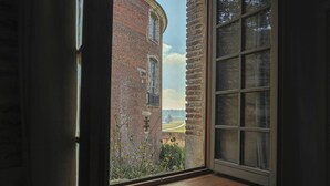 Una ventana con vistas a un edificio de ladrillo y un paisaje verde.