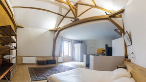 Un dormitorio con techo de madera, una cama, un escritorio y una estantería.