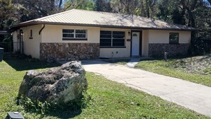 A single-story house with a stone foundation, a metal roof, and a front door. - OG Original House "Pet's Stay Free Bring Your Humans!" (Homosassa)