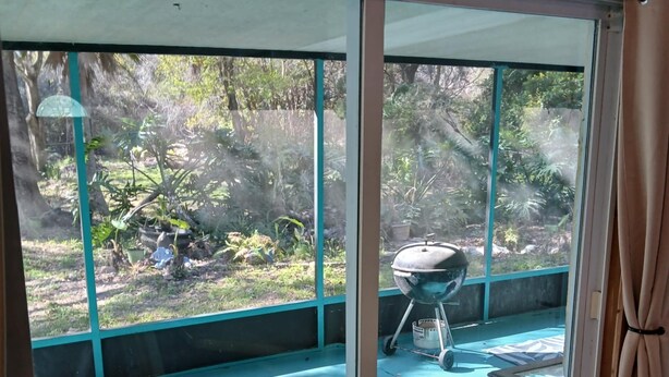 A room with a sliding glass door leading to a backyard with a barbecue grill and a small table. - OG Original House "Pet's Stay Free Bring Your Humans!" (Homosassa)