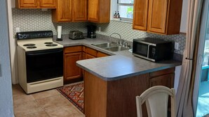 A kitchen with wooden cabinets, a stove, a microwave, and a sink. - OG Original House "Pet's Stay Free Bring Your Humans!" (Homosassa)