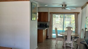 A spacious living area with a dining table and chairs, a kitchen with wooden cabinets, and a ceiling fan. - OG Original House "Pet's Stay Free Bring Your Humans!" (Homosassa)