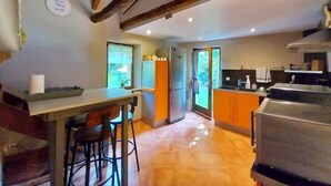 Una cocina moderna con una isla central, taburetes de bar, un refrigerador y una parrilla.