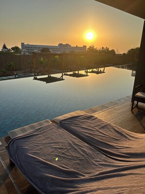 Ein sonnendurchfluteter Infinity-Pool mit Liegestühlen und Blick auf ein Gebäude mit der Aufschrift 'Café Maris'.