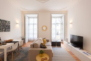 Un salon moderne avec un canapé, une table basse et un téléviseur. On y trouve également un coin repas avec des chaises et une table.