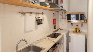 A compact kitchen with a sink, stove, microwave, and a small refrigerator.