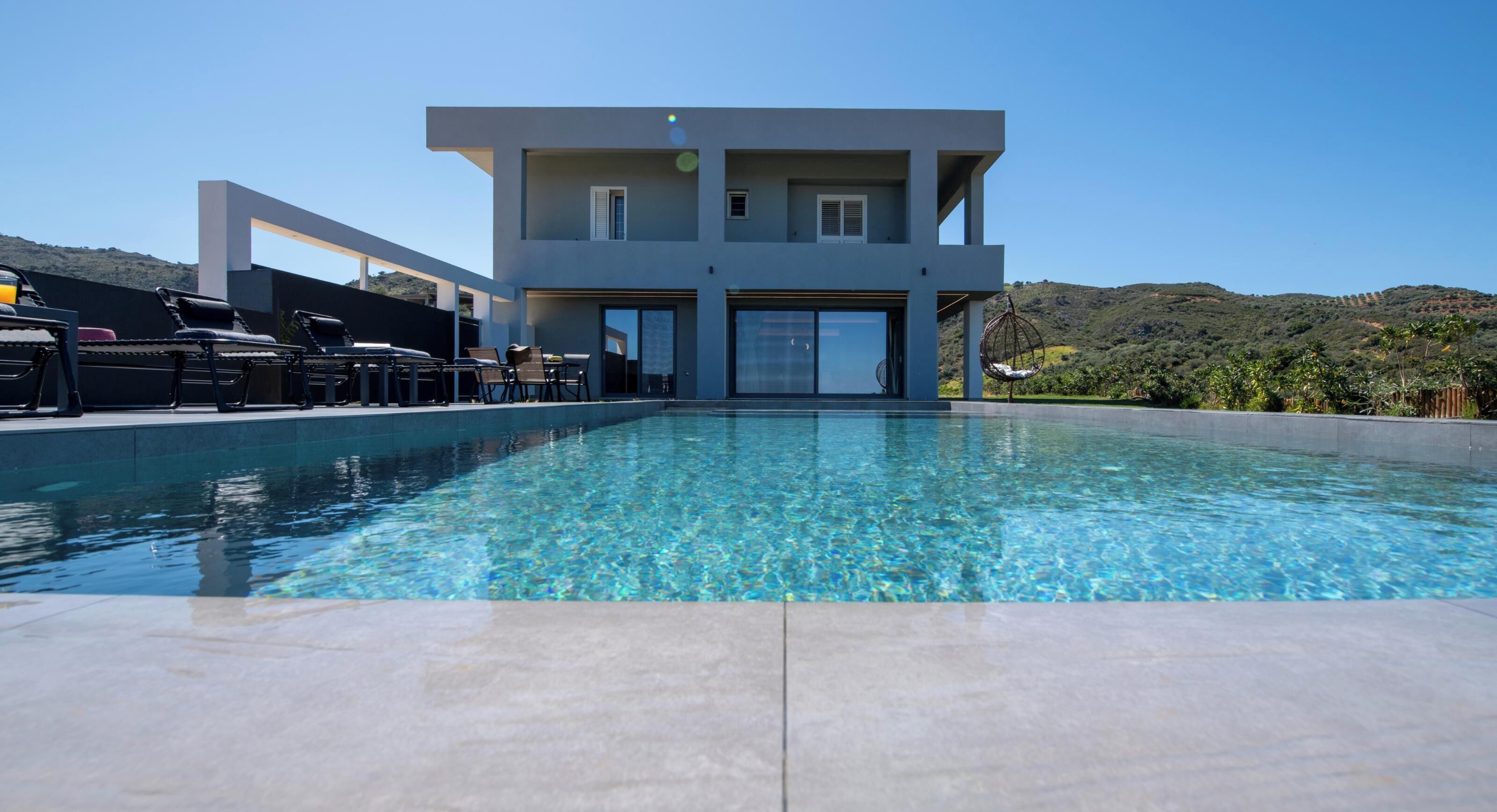 A modern two-story building with a swimming pool in front.