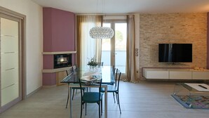 A modern living room with a dining area, a TV, and a fireplace. - Villa Giuly (Sirmione)