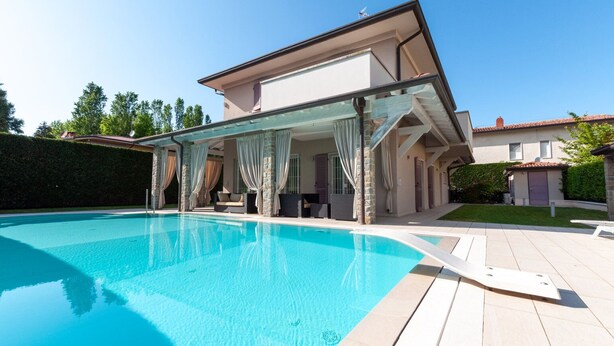 A modern house with a swimming pool, covered outdoor seating area, and a well-maintained garden. - Villa Giuly (Sirmione)
