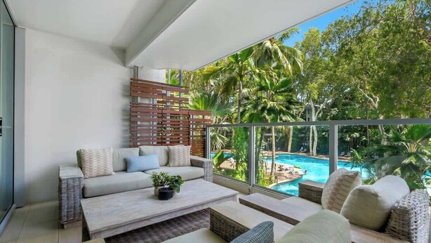 Uma sala de estar moderna com sofá, mesa de centro e vista para uma piscina.
