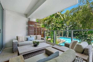 A modern living room with a sofa, coffee table, and a view of a swimming pool.
