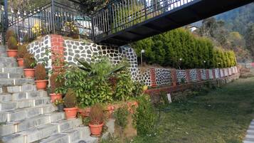 A staircase with potted plants, a stone wall, and a metal railing.