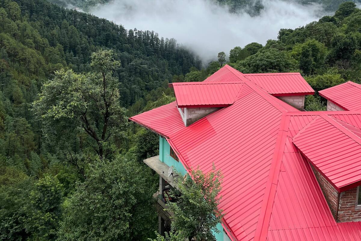A mountainous landscape with a red-roofed building surrounded by lush greenery.