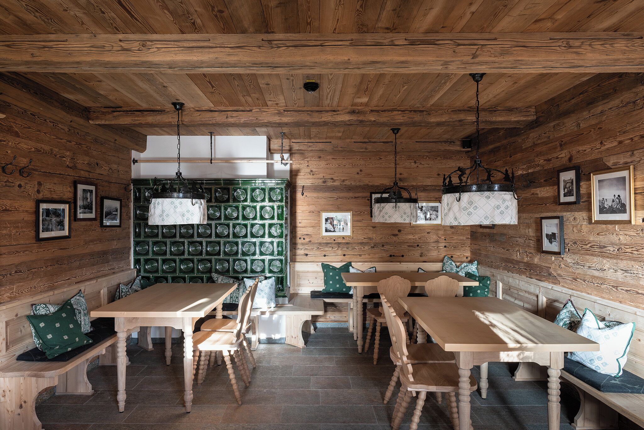 Un interior rústico de madera con una larga mesa de comedor, bancos y lámparas colgantes.