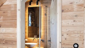 Interior de madera con baño a la vista, que incluye un lavamanos y espacio para toallas.