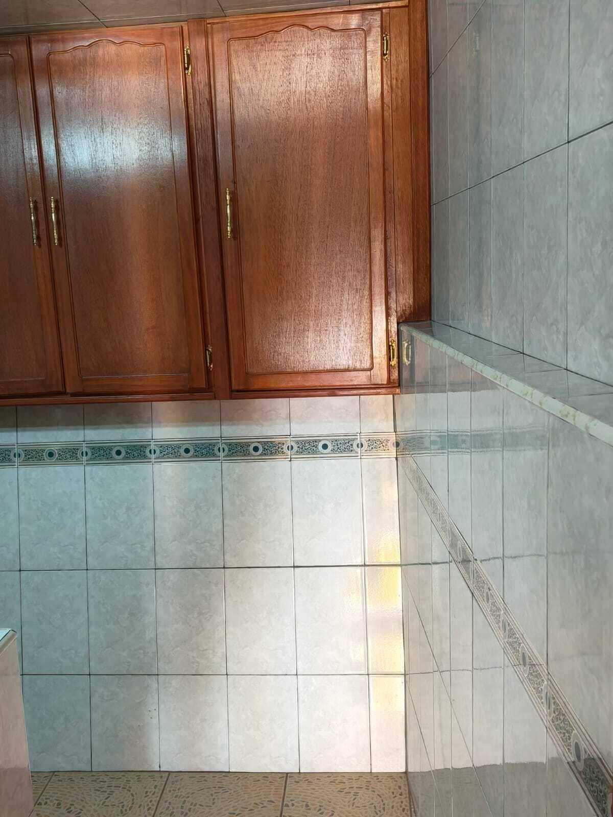 Una cocina con armarios de madera, suelo de baldosas y un detalle decorativo.