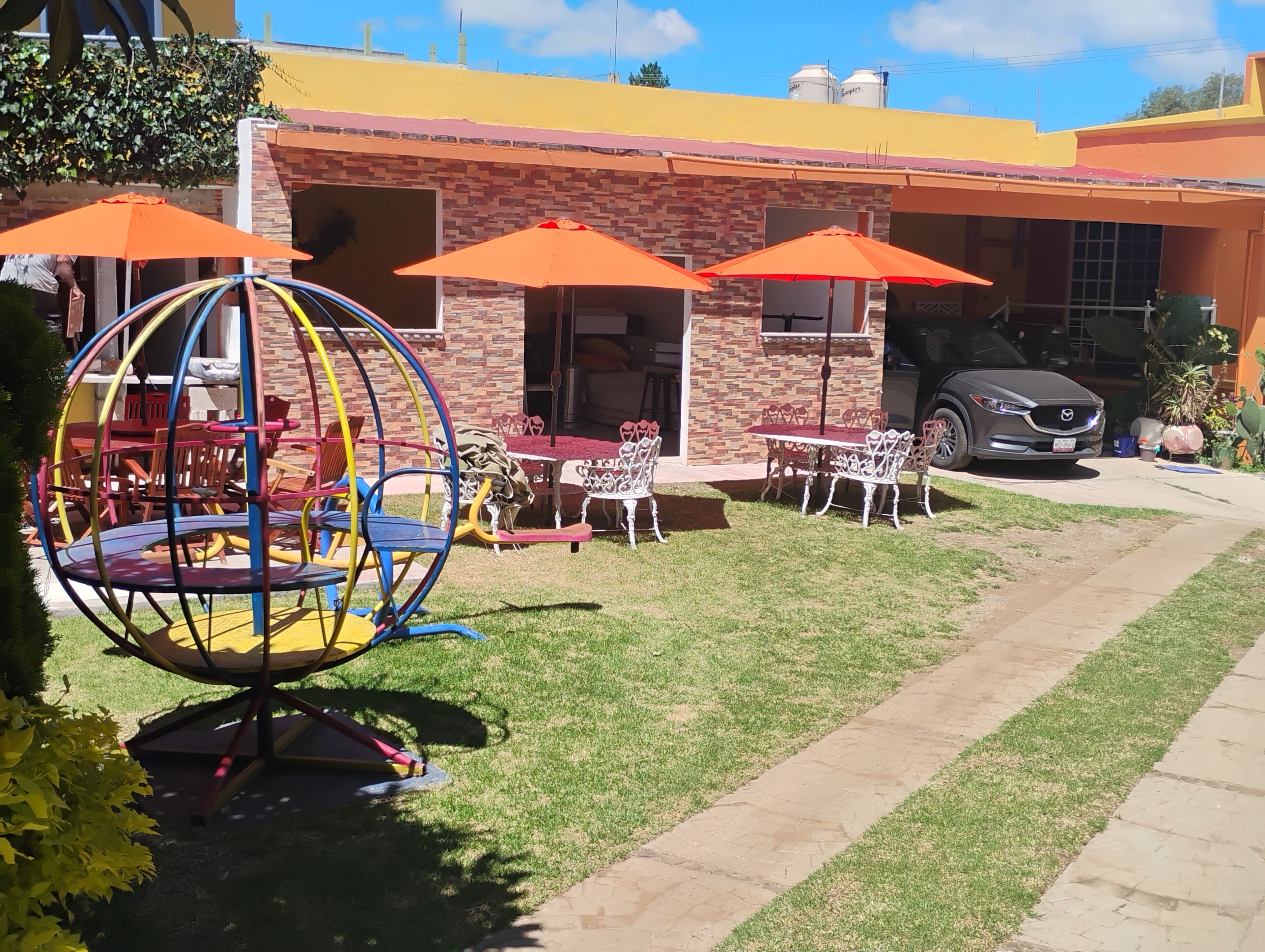 A patio area with outdoor seating, a children's play structure, and a parked car.
