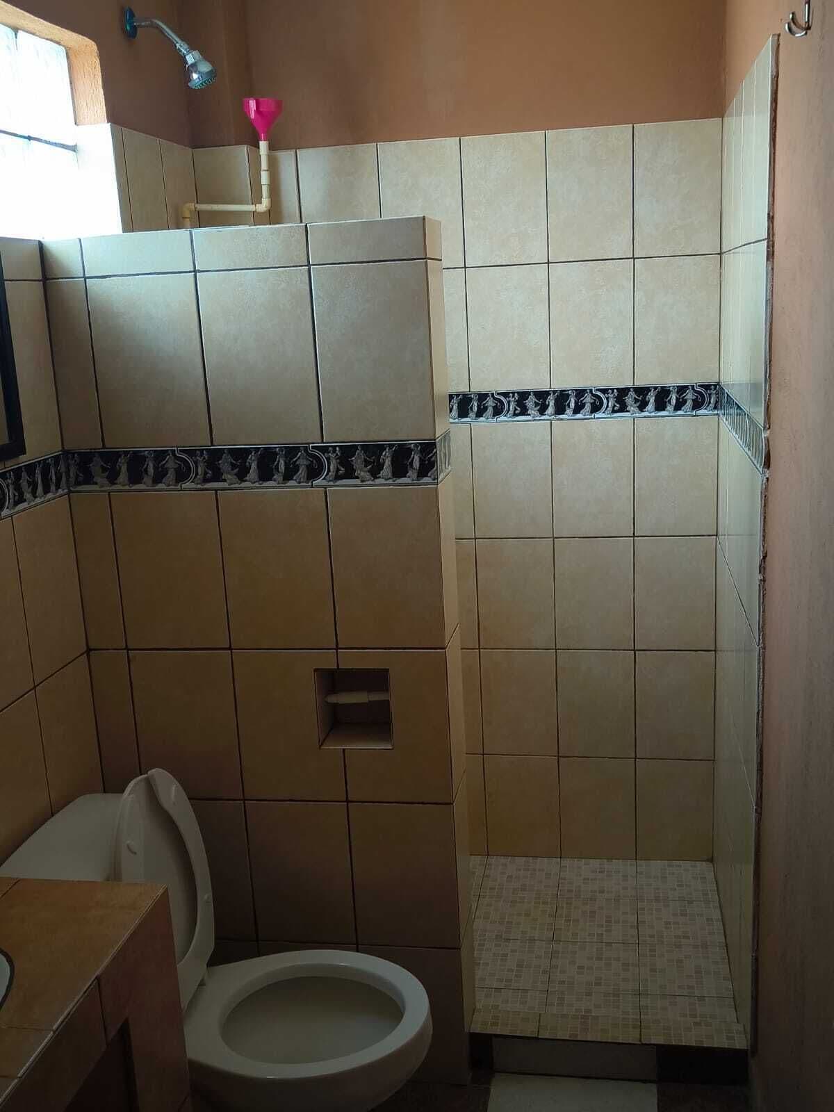 A bathroom with a toilet, a shower, and a sink.