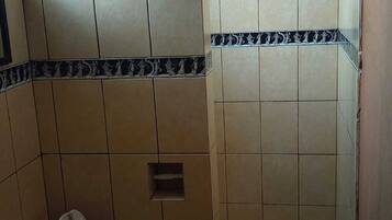A bathroom with a toilet, a shower, and a sink.