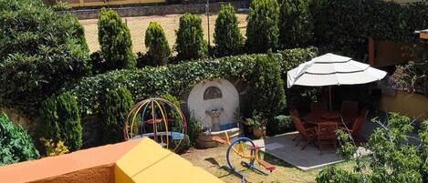 A courtyard with a play area, a seating area, and a view of buildings in the background.