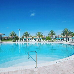 Piscina com espreguiçadeiras e palmeiras.