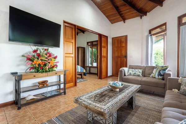 A living room with a TV, sofa, coffee table, and a floral centerpiece.