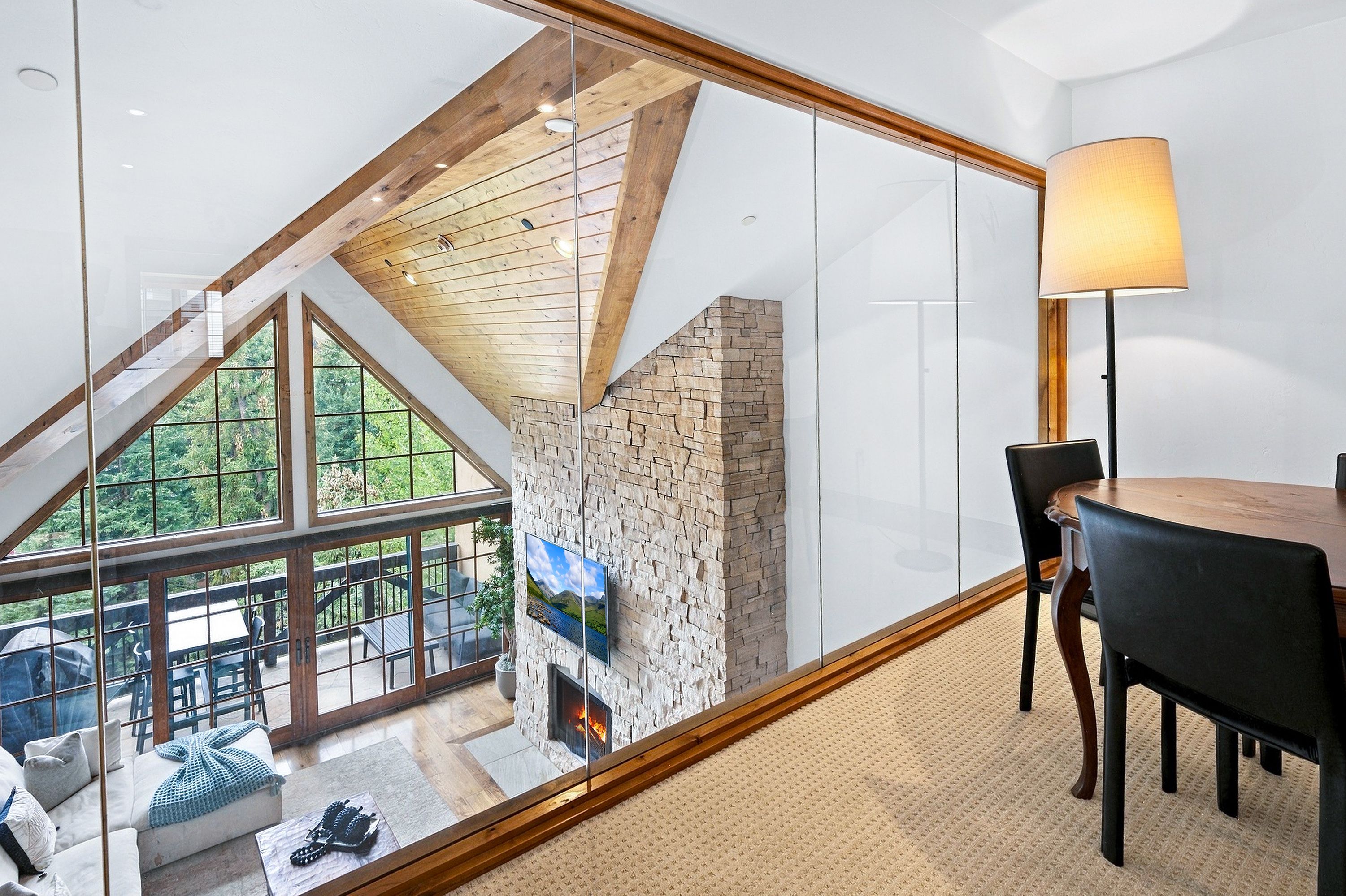 Un interior moderno con pared de vidrio, chimenea y comedor.