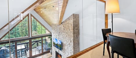 Un interior moderno con pared de vidrio, chimenea y comedor.