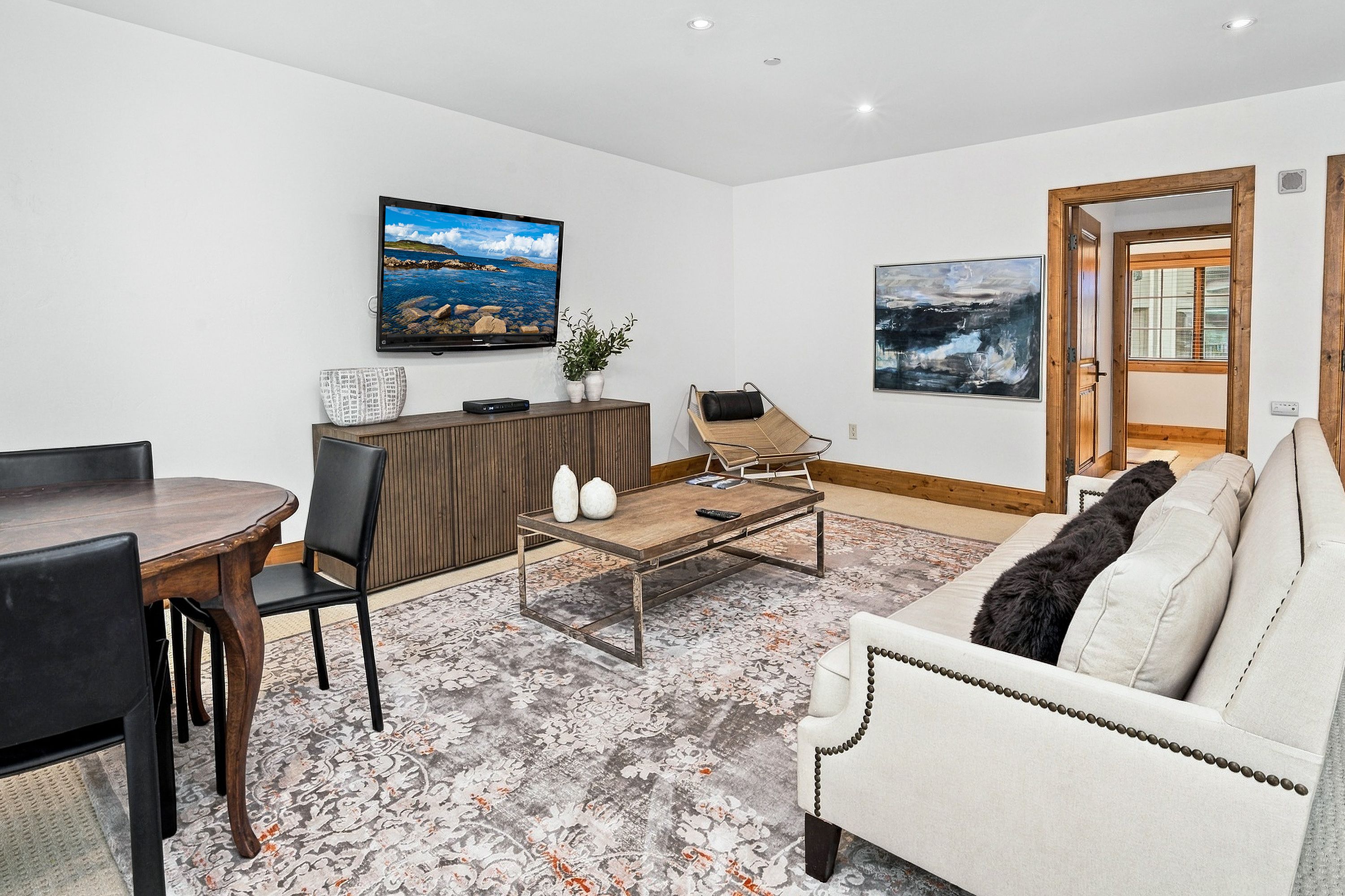 Ein modernes Wohnzimmer mit Essbereich, einem flachbildfernseher an der Wand, einer Couch und einem Couchtisch.